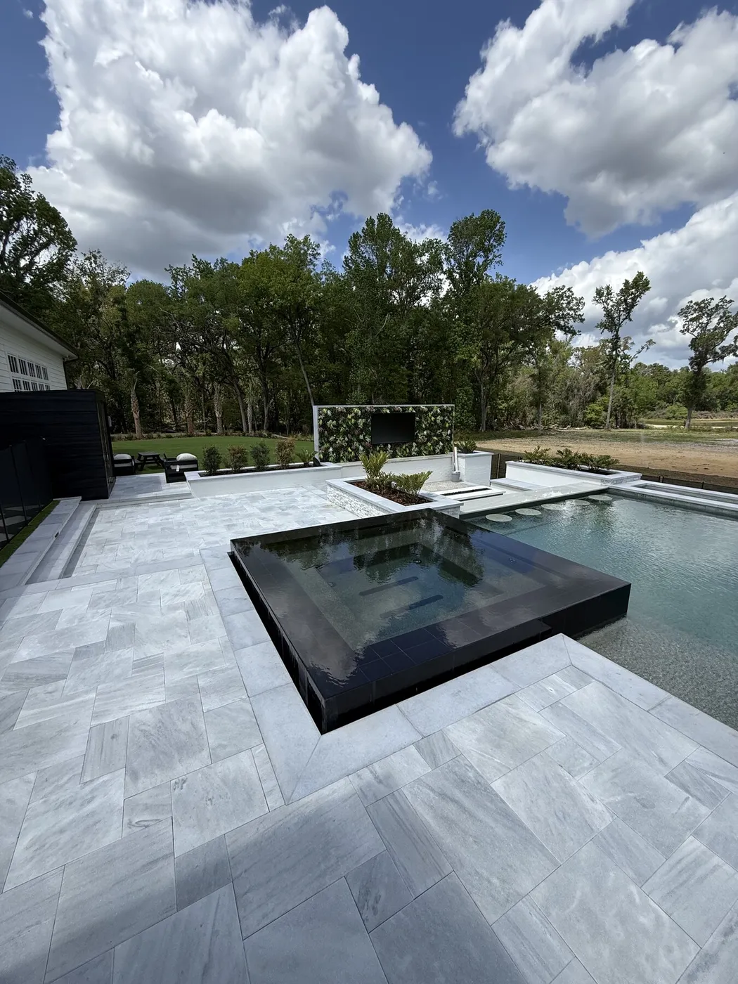 Light stone pool deck around a raised spa and pool
