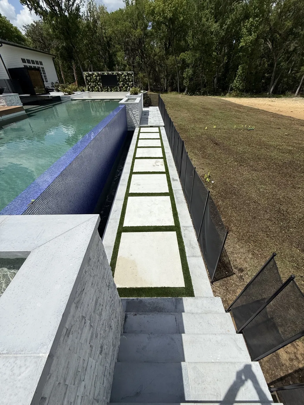 Stone stepping pads set into turf along the pool