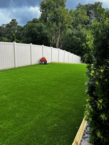 Artificial grass installed in a residential backyard with white fencing in Tampa, FL