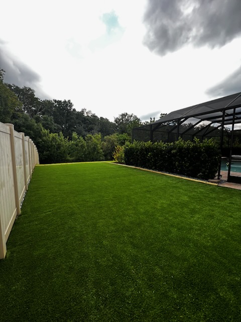 Spacious backyard with durable artificial turf near a screened patio enclosure